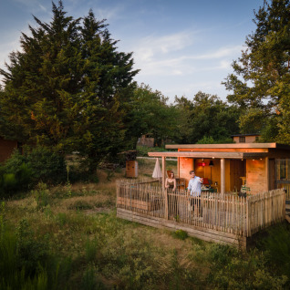 Hébergement glamping Village Huttopia Pays de Condrieu, cabane bois avec terrasse dans un cadre verdoyant.