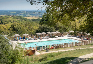 Blick auf den Poolbereich mit Sonnenliegen und Schirmen im Village Huttopia Pays de Condrieu, Auvergne-Rhône-Alpes.