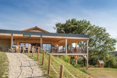 Træbygget glamping-reception med terrasse i Village Huttopia Pays de Condrieu, Auvergne-Rhône-Alpes.