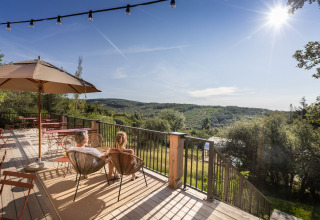 Zwei Personen genießen den Panoramablick von der Terrasse des Village Huttopia Pays de Condrieu Glampings.