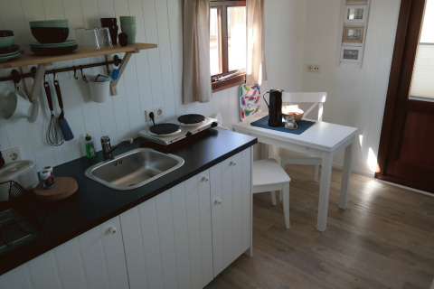 Interieur van glampingverblijf op Campingplatz am Nordseestrand met compacte keuken en eetruimte.