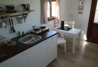 Intérieur d’un hébergement glamping au Campingplatz am Nordseestrand avec kitchenette et coin repas.