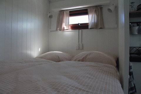Interior view of a cozy bed in the Zigeunerwagen Oost-Friesland glamping at Campingplatz am Nordseestrand.