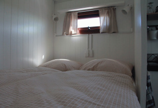 Knusse binnenfoto van bed in Zigeunerwagen Oost-Friesland glamping op Campingplatz am Nordseestrand.