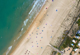 Vue aérienne de Camping Beauregard Plage - Glamping Languedoc-Roussillon avec plage et parasols.