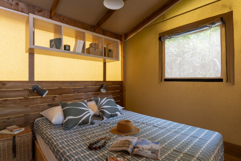 Camera glamping accogliente al Camping Beauregard Plage con arredamento in legno e letto matrimoniale.