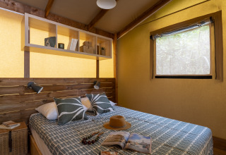 Knusse glamping slaapkamer bij Camping Beauregard Plage met houten accenten en comfortabel tweepersoonsbed.