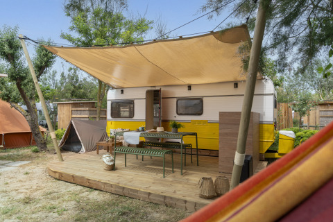Alojamiento glamping en Camping Beauregard Plage, Languedoc-Roussillon, caravana con terraza y sombra.