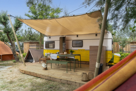 Glamping accommodatie op Camping Beauregard Plage - Languedoc-Roussillon, caravan met veranda en schaduw.