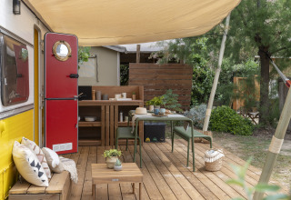 Glamping accommodation at Camping Beauregard Plage in Languedoc-Roussillon with deck, red door, and outdoor dining area.