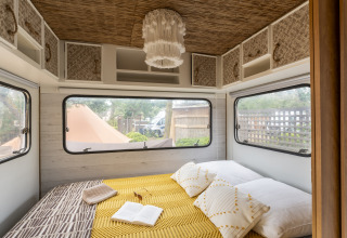 Gemütliche Glamping-Unterkunft im Camping Beauregard Plage, Languedoc-Roussillon, mit Doppelbett und Fenstern.