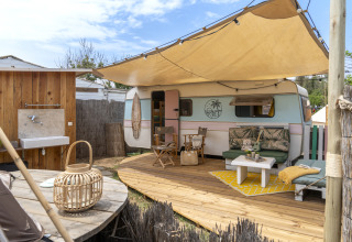 Glamping all'aperto con roulotte retrò, terrazza in legno e zona relax al Camping Beauregard Plage.