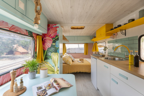 Colorful glamping accommodation interior with floral decor and modern kitchen at Camping Beauregard Plage, Languedoc.
