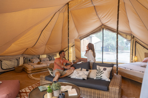 Vue intérieure d'une tente glamping luxueuse au Camping Beauregard Plage, Languedoc-Roussillon, avec des invités détendus.