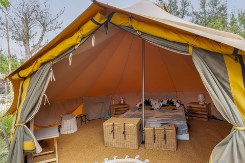Glamping-telt med hyggelig indretning og dobbeltseng på Camping Beauregard Plage, Languedoc-Roussillon.