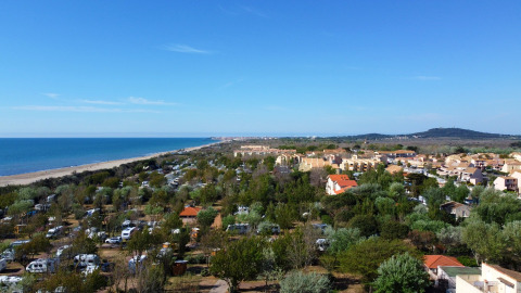 View of Camping Beauregard Plage - Glamping Languedoc-Roussillon with tents, cabins, and a scenic coastline.