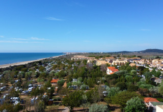 Vue sur Camping Beauregard Plage - Glamping Languedoc-Roussillon avec tentes, cabanes et plage en arrière-plan.