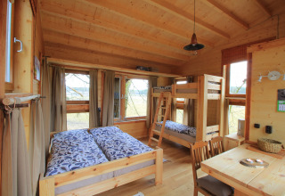 Gezellige boomhut met tweepersoonsbed, stapelbed en eetruimte bij Boomhuthotel Uckermark in Brandenburg.