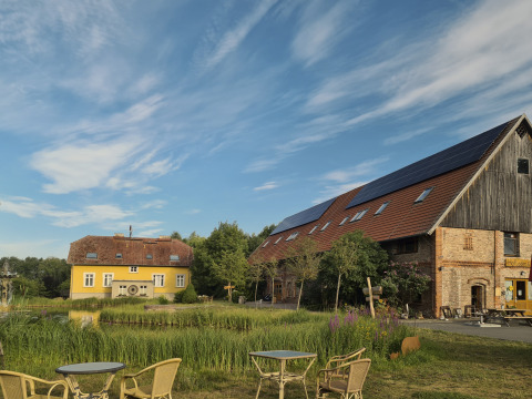 Alloggio glamping al Boomhuthotel Uckermark, Brandeburgo, tra edifici rurali, stagno e natura verdeggiante.