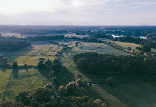 Luchtfoto van glamping Boomhuthotel Uckermark in Brandenburg, omgeven door groene velden en bossen.