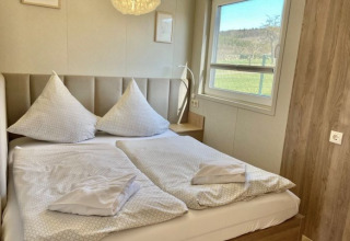 Moderne glamping accommodatie bij Camping Rhön Feeling - Tiny Houses Thüringen met tweepersoonsbed en raam.