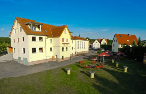 Blick auf Camping Rhön Feeling - Tiny Houses Thüringen mit Außenbereich, Sitzgelegenheiten und Sonnenschein.