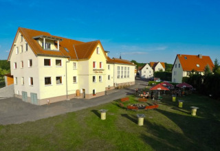 Udsigt over Camping Rhön Feeling - Tiny Houses Thüringen med udendørs siddepladser og solrige omgivelser.