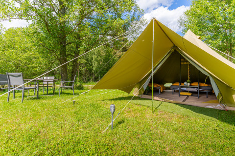 Glampingtent met bedden en buitensalon bij Les Jardins de Biffontaine, midden in het groen van de Vogezen.