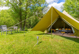 Glampingtelt med senge og udendørs siddeområde i grønne omgivelser hos Les Jardins de Biffontaine.