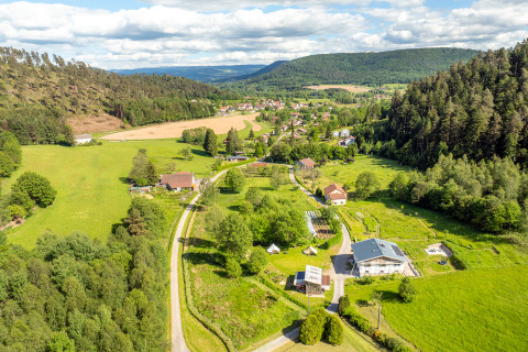Luchtfoto van Les Jardins de Biffontaine Glampingtenten Vogezen met groene velden, bossen en landelijke huizen.