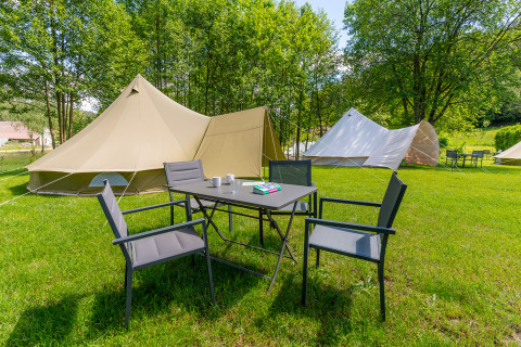 Zona de glamping con tiendas de lujo y mesa al aire libre en Les Jardins de Biffontaine, Vosgos.