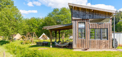 Glamping stay at Les Jardins de Biffontaine with tents, playground, and wooden lodge in scenic nature.