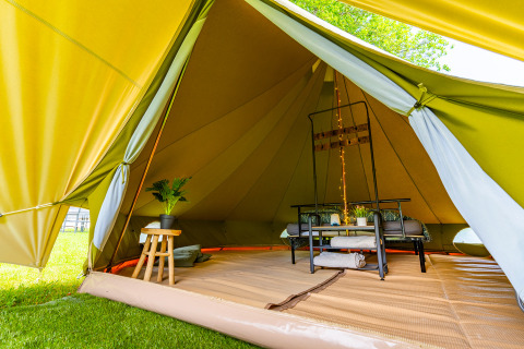 Innenaufnahme eines luxuriösen Glampingzelts mit moderner Einrichtung und grünen Pflanzen im Vogesen.