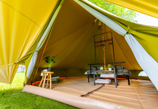 Vista interior de una lujosa tienda glamping con muebles modernos y plantas en Les Jardins de Biffontaine.