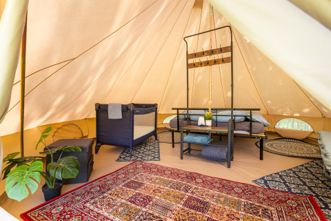 Gemütliches Glamping-Zelt mit Teppichen, Pflanzen und Bett im Les Jardins de Biffontaine, Vogesen, abgebildet.