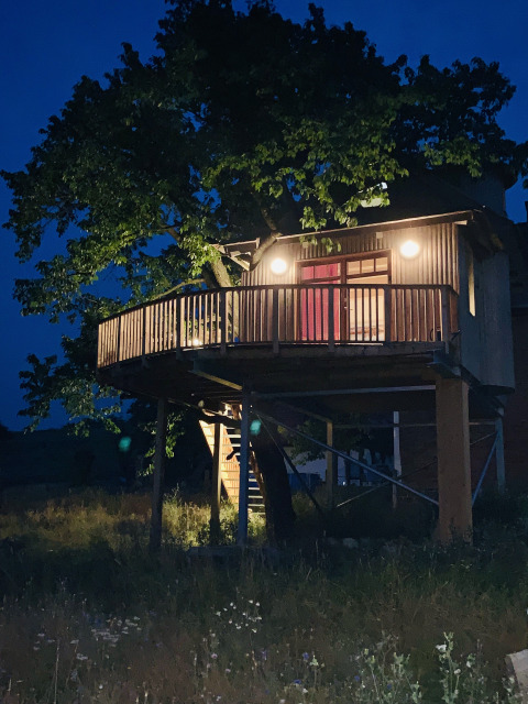 Alojamiento glamping o camping llamado 'Boomhut Wesertal - Boomhutten Hessen' en los Países Bajos de noche.