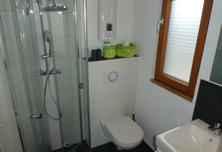 Bagno da campeggio moderno con doccia in vetro, wc sospeso e lavandino presso Boomhut Wesertal, Hessen.