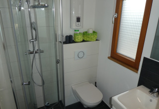 Modernes Campingbad mit Duschkabine, Wandtoilette und Waschbecken in der Boomhut Wesertal, Hessen.