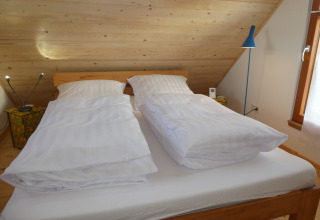 Área de descanso en Boomhut Wesertal - Boomhutten Hessen con dos edredones individuales en cama doble.