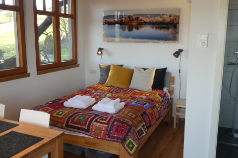 Sfeervol interieur van Boomhut Wesertal - Boomhutten Hessen met kleurrijk beddengoed en natuurzicht.