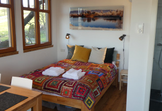 Gemütliche Unterkunft im Boomhut Wesertal - Boomhutten Hessen mit buntem Bett und Fensterblick auf Natur.