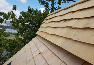Close-up van het houten dak van een boomhutaccommodatie bij water, glamping in de Hessen regio.