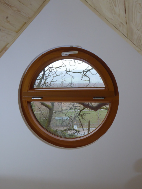 Round window in Boomhut Wesertal - Boomhutten Hessen glamping accommodation with a view of nature.