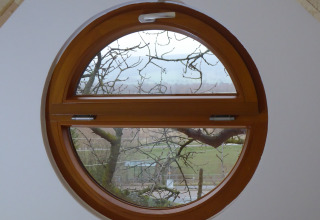 Fenêtre ronde dans Boomhut Wesertal - Boomhutten Hessen, hébergement glamping avec vue sur la nature.