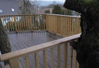 Wooden terrace with railing built around a tree, Boomhut Wesertal glamping accommodation in Hessen, Germany