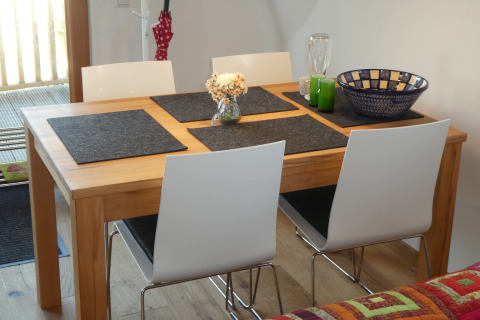 Dining area with wooden table, four white chairs, and decor in glamping accommodation Boomhut Wesertal - Boomhutten Hessen.