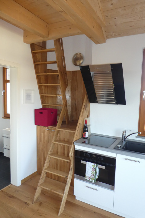 Escalera de madera junto a una pequeña cocina en el glamping Boomhut Wesertal de Hesse.