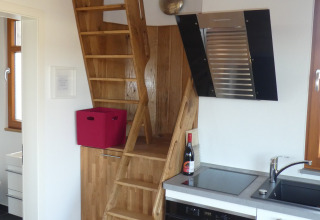 Escalera de madera junto a una pequeña cocina en el glamping Boomhut Wesertal de Hesse.