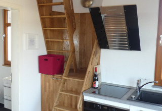 Scala interna in legno accanto a una cucina compatta nel glamping Boomhut Wesertal in Assia.