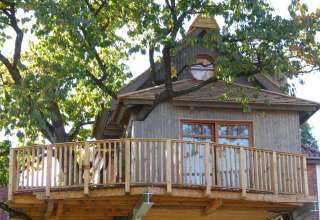 Treehouse glamping accommodation at Boomhut Wesertal in Hesse, built around a tree with a spacious deck.